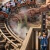 東京ディズニーランドの人気アトラクション「ビッグサンダー・マウンテン」の前に立つキャストと、身長計で身長を測る子供。アトラクションに乗っている家族連れが笑顔で通過している。