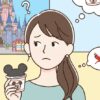 ディズニーリゾートのシンデレラ城を背景に、ミッキーマウスのカップラーメンを手に持ち、美味しいのか悩んでいる日本人女性のイラスト。女性の頭上には、美味しい顔と美味しくない顔の絵文字があり、カップラーメンの味について考えている様子が描かれている。