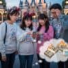ディズニーリゾートでスマートフォンのホテル予約サイトを見て、宿泊費の高さに悩む家族の様子