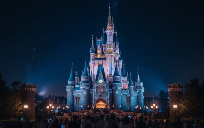 ライトアップされた夜のシンデレラ城に向かって歩く来園者の群衆。ウィークナイトパスポートでの夜の入園を想起させる。